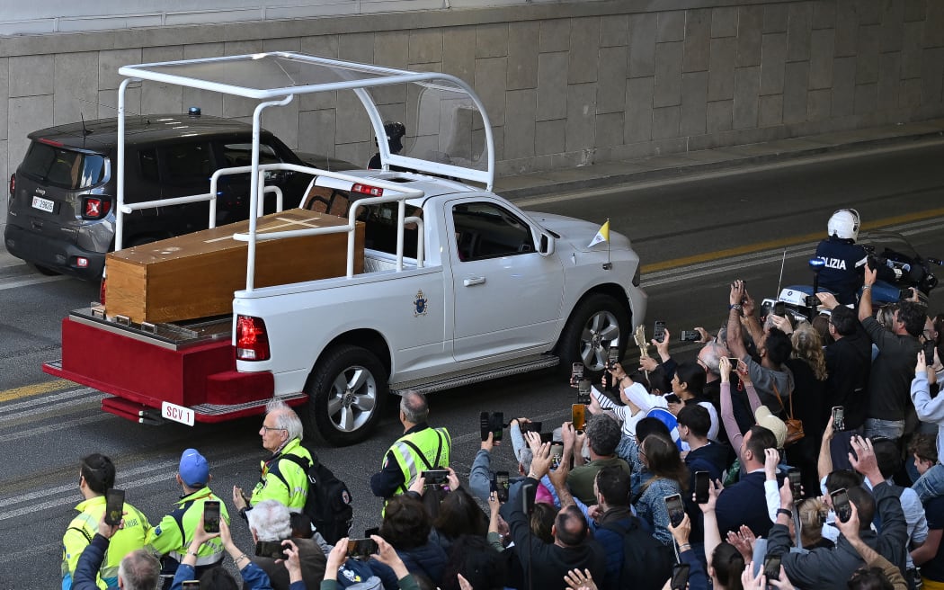 People gather along the road as the coffin of late Pope Francis is transported from St Peter's Basilica to Santa Maria Maggiore Basilica, during the funeral ceremony in Rome on April 26, 2025. (Photo by Andrej ISAKOVIC / AFP)