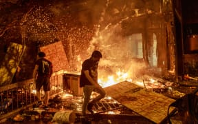 Protesters walk past burning debris outside the Third Police Precinct on May 28, 2020 in Minneapolis, Minnesota, during a protest over the death of George Floyd.