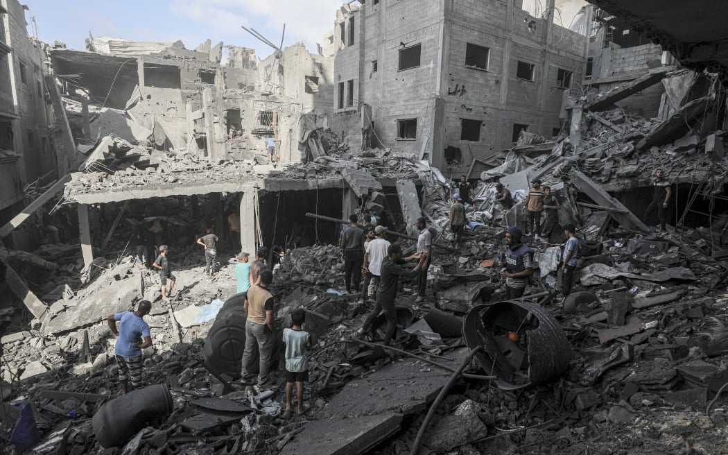 Palestinians gather amid piles of rubble from collapsed residential structures in Al-Shatea refugee camp in Gaza City, Palestinian territories on October 29, 2025. According to the Palestinian Ministry of Health, at least 110 Palestinians were killed and several others wounded as Israeli airstrikes hit multiple residential areas in the Gaza Strip. (Photo by Abood Abusalama / Middle East Images via AFP)
