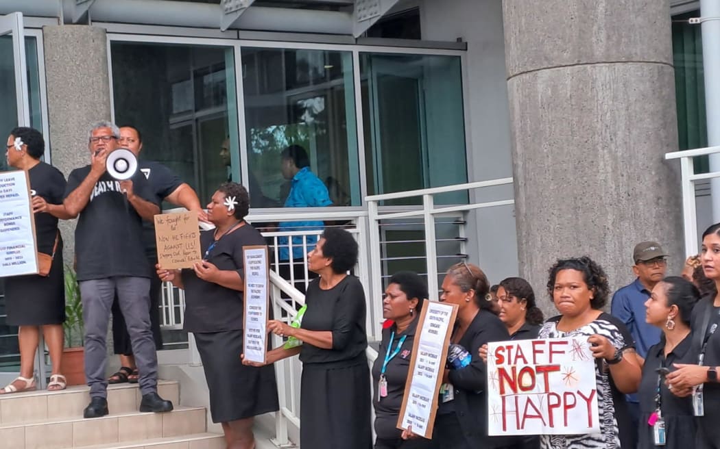 Aggrieved employees of the university showed up dressed in black, holding placards calling for “fair pay” and for Ahluwalia to resign.