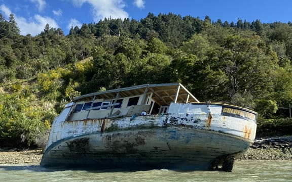 Old and damaged wooden fishing boat aground in Marlborough Sound