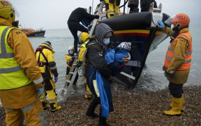 Migrants are helped ashore from a RNLI lifeboat at a beach in Dungeness, on the south-east coast of England.