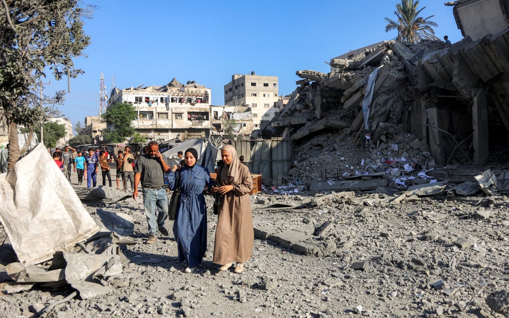 People walk past rubble in the aftermath of an Israeli strike on Salam Tower in Gaza City.