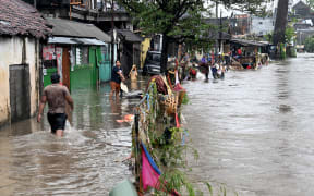 Residents wade through floodwaters in their neighbourhood following heavy rainfall in Denpasar, Indonesia's Bali island, on September 10, 2025. (Photo by SONNY TUMBELAKA / AFP)