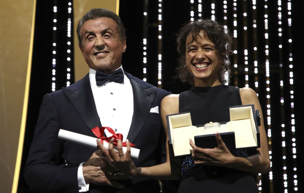Director Mati Diop, right, holds the grand prix Palme d'Or award for the film 'Atlantique' presented by actor Sylvester Stallone during the awards ceremony at tCannes, May 25, 2019.