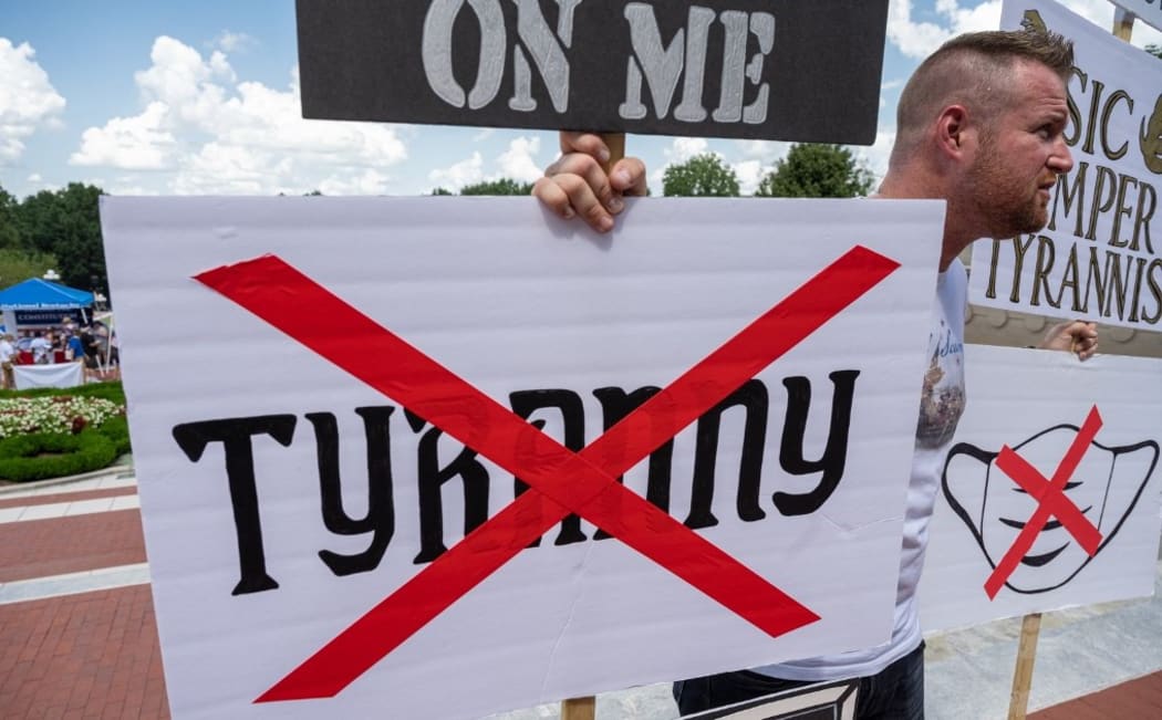 FRANKFORT, KY - AUGUST 28: A man holds a group of anti-mask and anti-tyranny signs during the Kentucky Freedom Rally at the capitol building on August 28, 2021 in Frankfort, Kentucky.