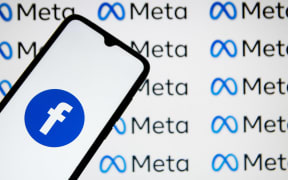 In this photo illustration a Facebook logo seen displayed on a smartphone with Meta logos in the background in Athens, Greece on December 19, 2021.
