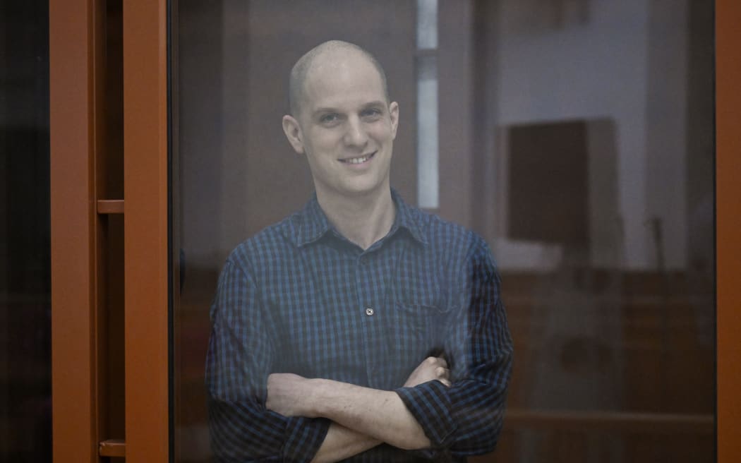 US journalist Evan Gershkovich, accused of espionage, smiles from inside a glass defendants' cage prior to a hearing in Yekaterinburg's Sverdlovsk Regional Court on June 26, 2024. (Photo by NATALIA KOLESNIKOVA / AFP)