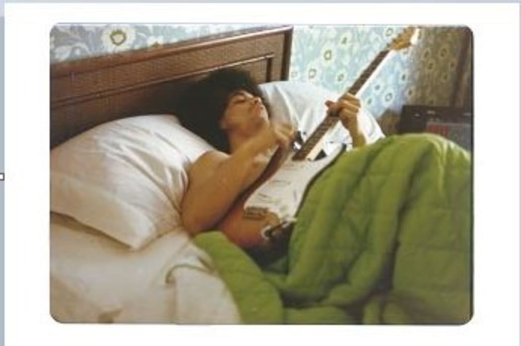 Prince plays a guitar in bed at his new home on France Avenue, April 1978.