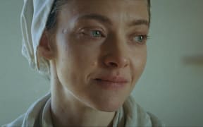 Amanda Seyfriend, wearing a headscarf, looks emotional and barefaced.