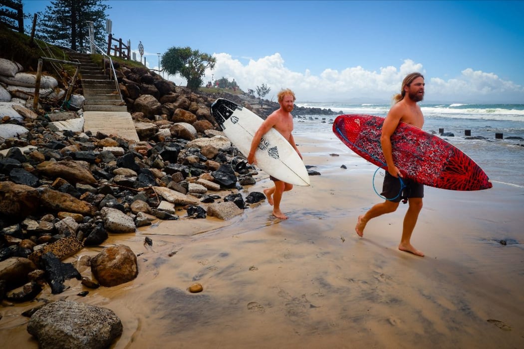 Two surfers negotiate massive beach erosion in the wake of cyclonic conditions at Byron Bay Main Beach on December 15, 2020, after wild weather lashed Australia's Northern New South Wales.