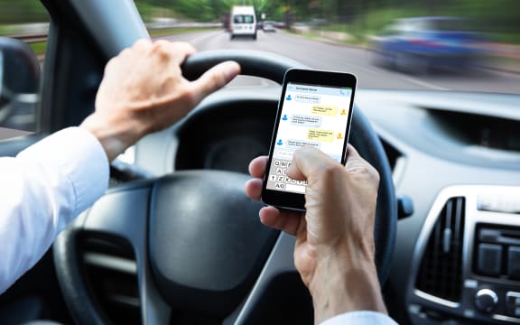 Close-up Of A Man's Hand Typing Text Message On Mobile Phone While Driving Car