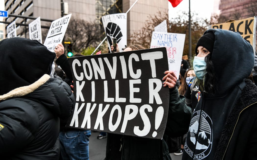 People hold placards as they protest outside of the Courthouse during the trial of former Minneapolis police officer charged with murdering George Floyd in Minneapolis, Minnesota on April 19, 2021.