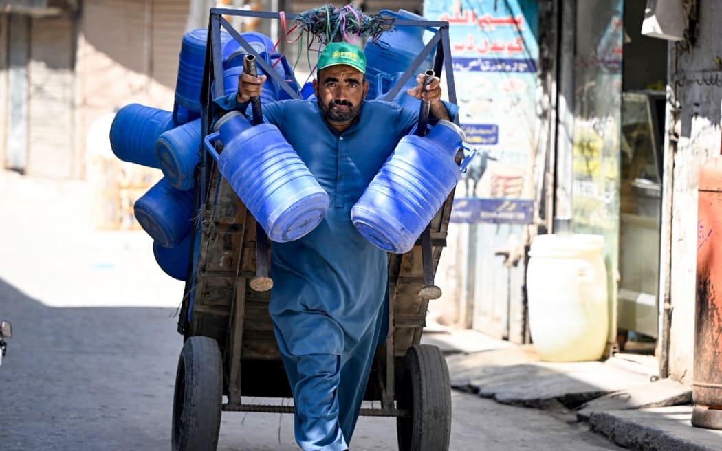 A worker pulls a pushcart loaded with empty water bottles during sweltering heat at a market in Rawalpindi on June 12, 2024. (Farooq Naeem/AFP)