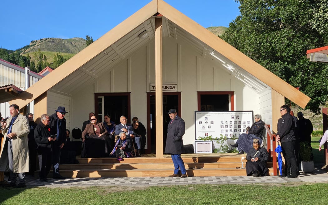 Te Arikinui Kuini Ngawai hono i te po (seated left) sits below the māhau of the new whare.