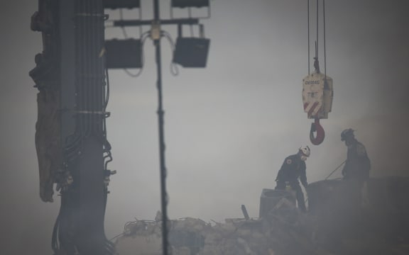 Rescue workers look for possible survivors among the debris of a partially collapsed building