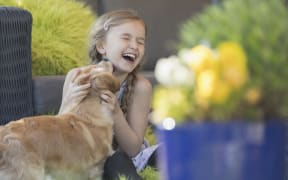 Dog kissing laughing girl on patio. (Photo by CAIA IMAGE/SCIENCE PHOTO LIBRARY / NEW / Science Photo Library via AFP)