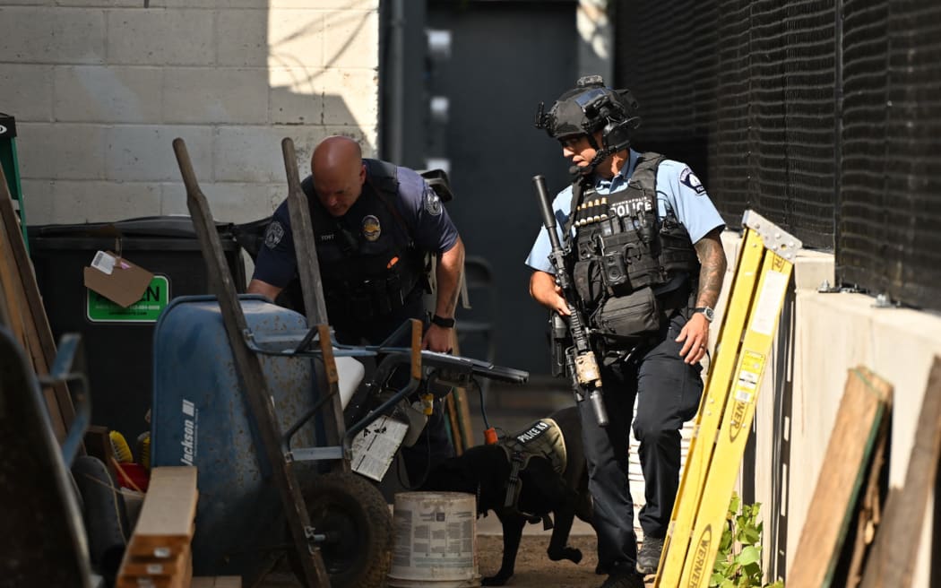 Police officers search an alleyway near the scene of a shooting at Annunciation Catholic School in Minneapolis, Minneosta, on August 27, 2025.