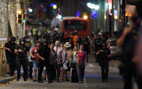 Policemen accompany clients of a store outside a cordoned off off area after a van ploughed into the crowd, killing 13 persons and injuring over 80 on the Rambla in Barcelona on August 17, 2017.