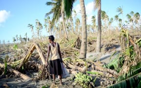 A woman carries bananas found amid the destruction caused by Cyclone Pam.