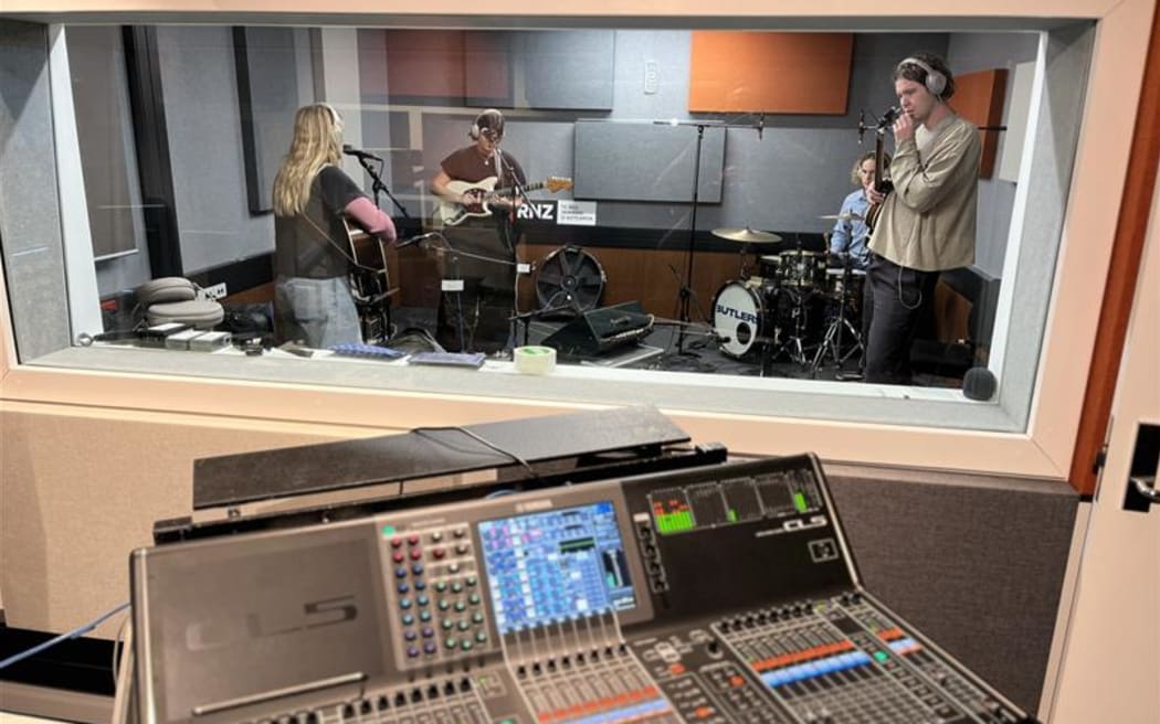This is a photo of the band 'There's a Tuesday' warming up for their NZ Live. The photo is taken from the mixing desk looking through the control room glass.