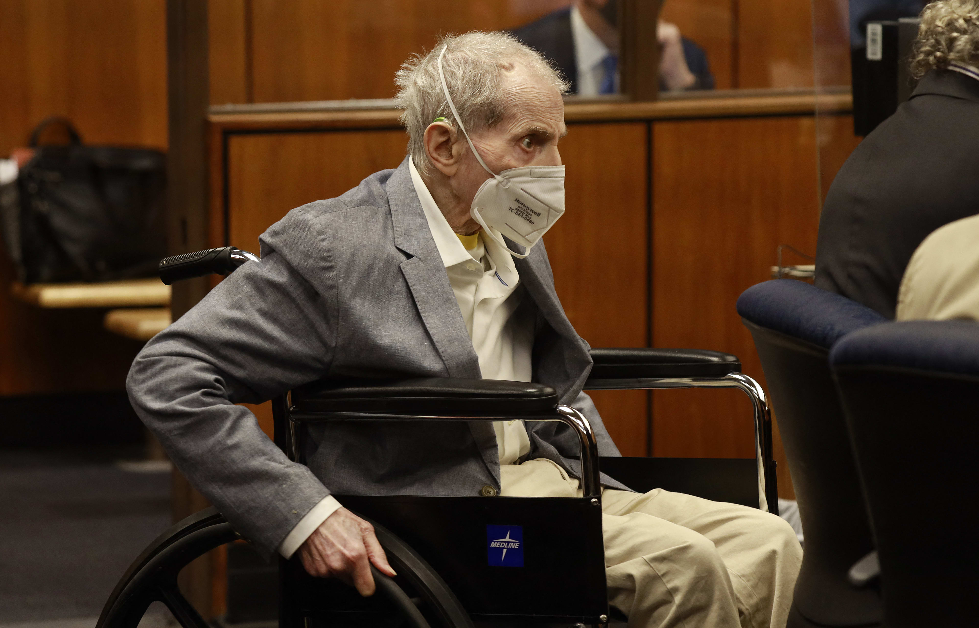 Robert Durst in his wheelchair spins in place as he looks at people in the courtroom.
