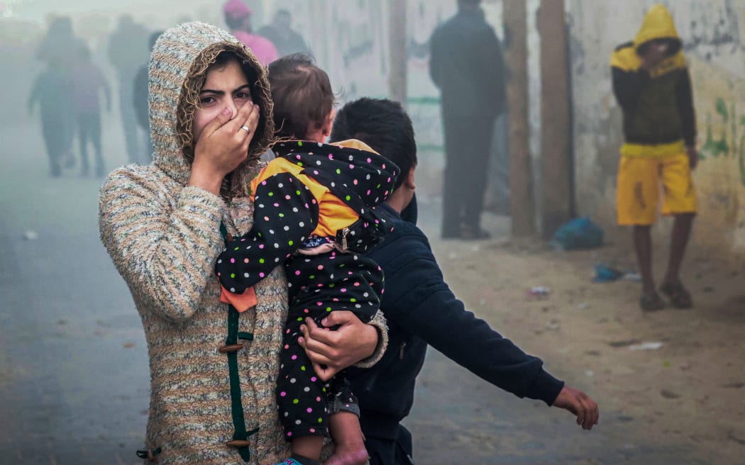 A woman holding a child flees following an Israeli strike in Rafah in the southern Gaza Strip on November 23, 2023, amid ongoing battles between Israel and the Palestinian militant group Hamas. (Photo by Mohammed ABED / AFP)