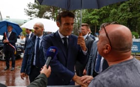 France's President Emmanuel Macron (C) speaks with onlookers as he leaves after casting his vote in the second stage of French parliamentary elections at a polling station in Le Touquet, northern France on 19 June 2022.