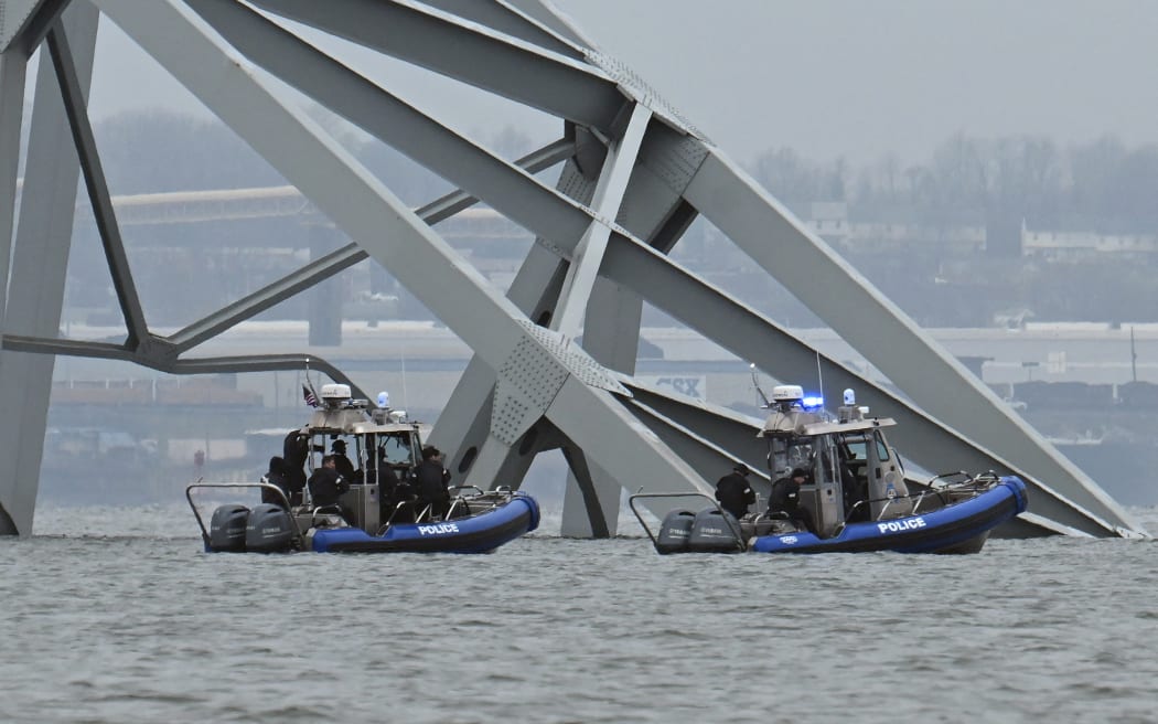 Police recovery crews work near the collapsed Francis Scott Key Bridge after it was struck by the container ship Dali in Baltimore, Maryland, on March 27, 2024. Authorities in Baltimore were set to focus on expanding recovery efforts on March 27 after the cargo ship slammed into the bridge, causing it to collapse and leaving six people presumed dead. All six were members of a construction crew repairing potholes on the bridge when the structure fell into the Patapsco River at around 1:30 am (0530 GMT) on March 26. (Photo by Jim WATSON / AFP)