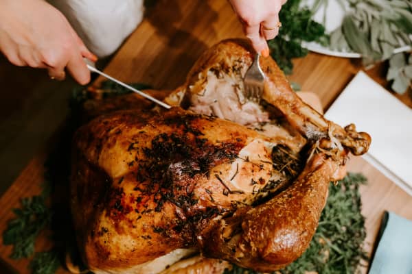 A person cuts open a cooked turkey on a dinner table.