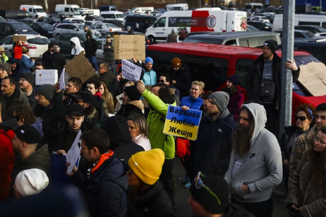 People hold cards with free accommodation and transport offer for Ukrainian citizens who arrive with a bus to a supermarket parking lot after crossing Ukrainian-Polish border in Medyka due to ongoing Russia's attacks on Ukraine.