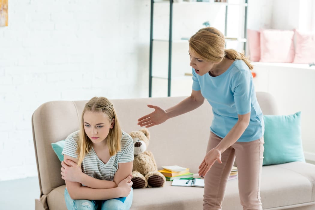 A photo of an angry mother yelling at teen daughter at home