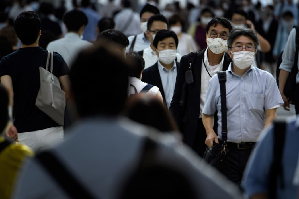 People wearing face masks walk during the evening rush hour from Shinagawa railway station in Tokyo on June 24, 2020.