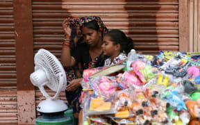 People sit in front of a table fan to cool off on a hot summer afternoon in Varanasi on May 29, 2024, amid ongoing heatwave. Temperatures in India's capital soared to a national record-high of 52.3 degrees Celsius (126.1 Fahrenheit) on May 29, figures from the government's weather bureau showed, as it warned of dangerous heat levels in the sprawling megacity. (Photo by Niharika KULKARNI / AFP)