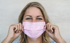 Young woman wearing pink face mask portrait - Blonde female using protective facemask for preventing spread of corona virus
