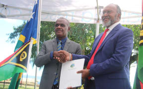 Solomon Islands Prime Minister Jeremiah Manele, left, and Vanuatu Prime Minister Charlot Salwai Tabimasmas shaking hands after the signing of the ‘Tirvau’ agreement.