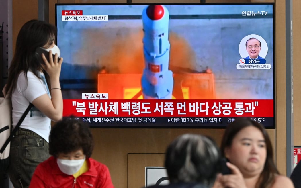 People watch a television screen showing a news broadcast with file footage of North Korea's rocket launch, at the Seoul Railway Station in Seoul on 31 May, 2023.