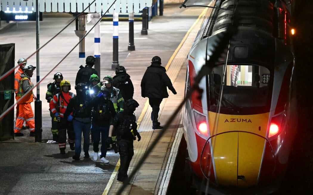 Police and British Transport Police officers walk on the platform alongside an LNER Azuma train at Huntingdon Station in Huntingdon, eastern England, on November 1, 2025, following a stabbing on a train. UK police said they had arrested two suspects Saturday as "a number of people" were taken to hospital after a stabbing on a train in Cambridgeshire, eastern England. "We are currently responding to an incident on a train to Huntingdon where multiple people have been stabbed," British Transport Police said on X, adding that "two people have been arrested". (Photo by JUSTIN TALLIS / AFP)