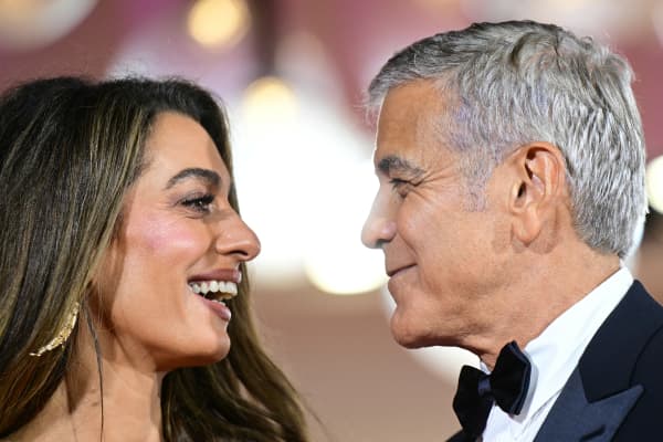US actor George Clooney holds the hand of his wife Amal Clooney as they walk the red carpet before the screening of the movie "Jay Kelly" presented in competition at the 82nd International Venice Film Festival, at Venice Lido on August 28, 2025.