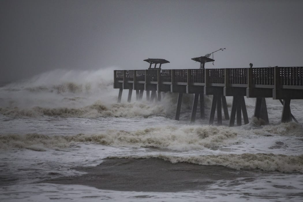 Waves crash around a pier in Jacksonville, Florida