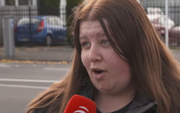 A woman with long brown hair speaks into a microphone