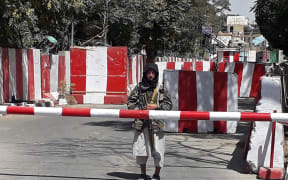 A Taliban fighter stands guard at the entrance of the police headquarters in Ghazni, on 12 August 2021, as Taliban move closer to Afghan capital after taking Ghazni city.
