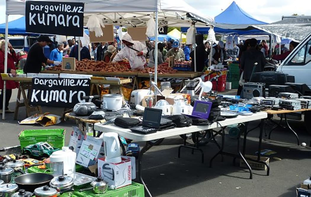Kumara with from Dargaville sign piled high behind stall with pots and pans etc