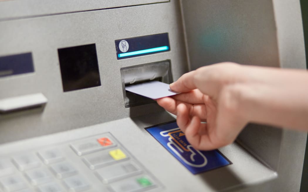 Someone takes off money from outdoor bank terminal, inserts plastic credit card in atm machine, going to withdraw money and get salary. Cash machine. Modern technologies and innovations concept