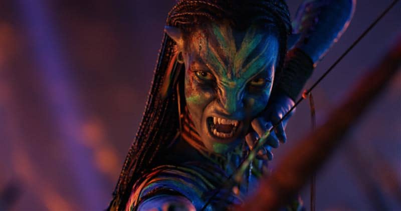 Neytiri has a multi-coloured face and a defensive snarl revealing sharp teeth.