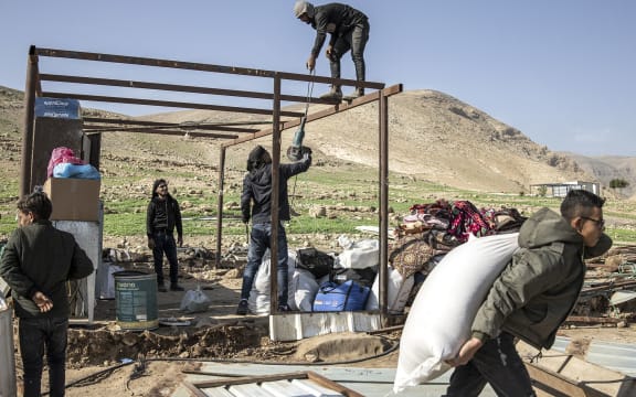 Men help dismantle a house as a Bedouin family pack their belongings and leave their home after months of harassment from a nearby illegal Israeli settler outpost in Ras Ein al-Auja, near Jericho in the Israel-occupied Palestinian West Bank on 8 January.