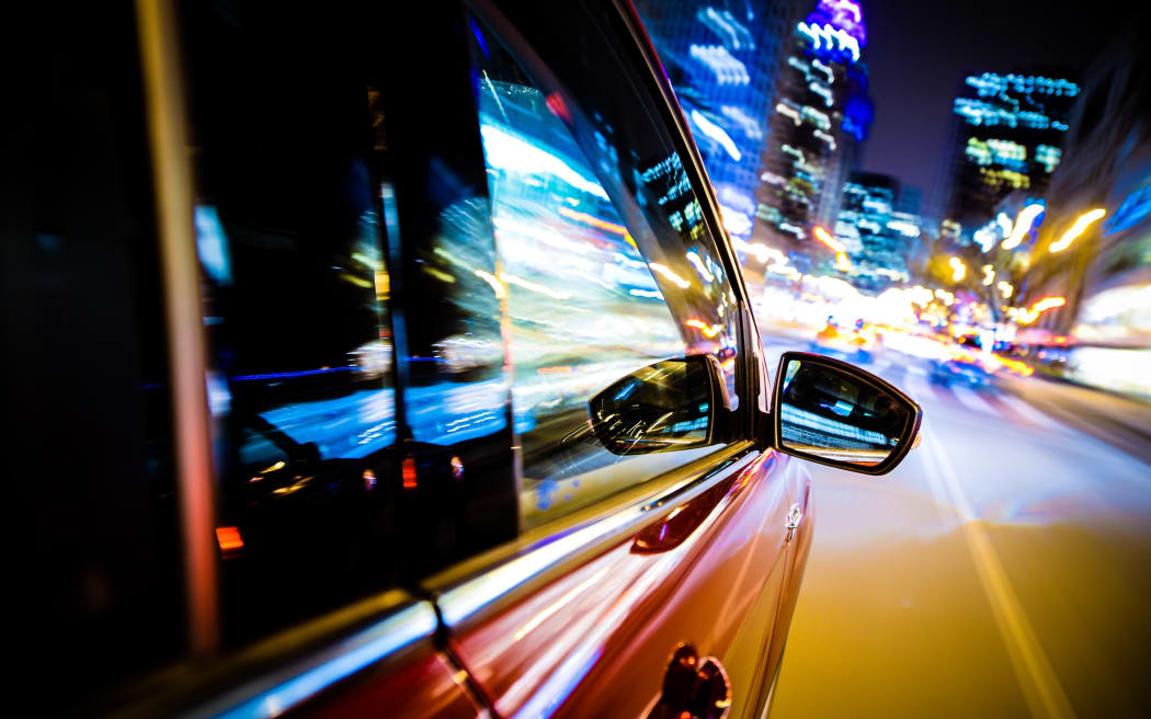 Driving Through City Lights. Car Side and Mirror View. Night Drive Concept