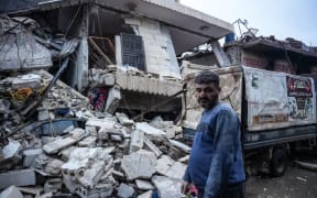 A resident stands in front of  a collapsed building following an earthquake in the town of Jandaris, in the countryside of Syria's northwestern city of Afrin in the rebel-held part of Aleppo province, on February 6, 2023. - Hundreds have been reportedly killed in north Syria after a 7.8-magnitude earthquake that originated in Turkey and was felt across neighbouring countries. (Photo by Rami al SAYED / AFP)