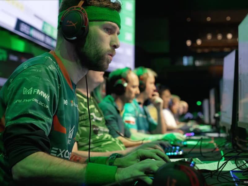 A line-up of men wear headphones and stare intently at individual screens.