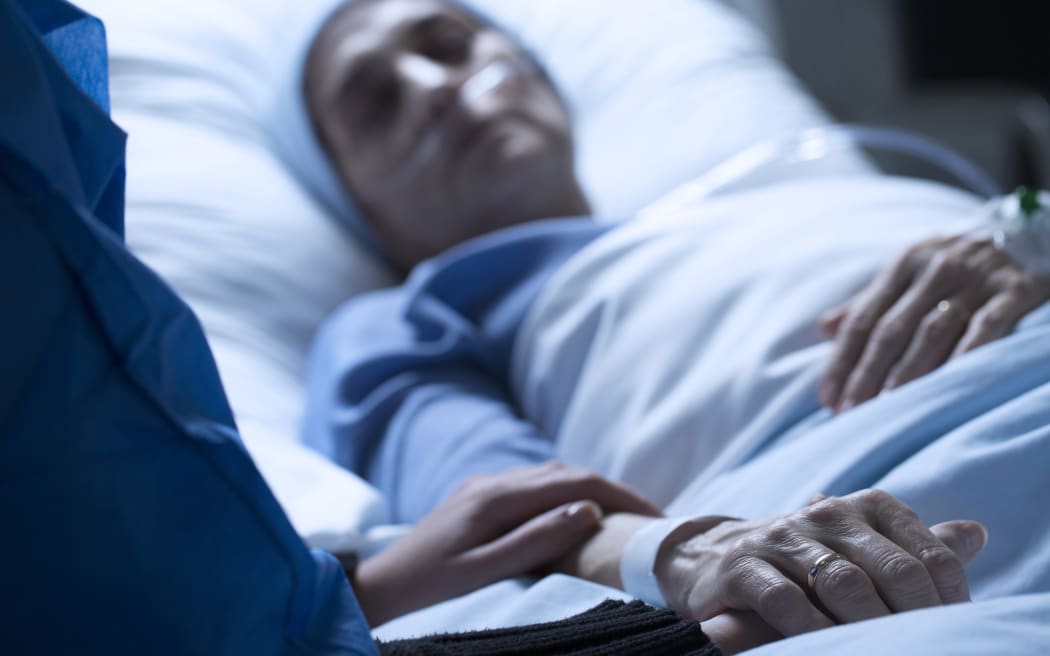 Young woman in hospice care, holding hands in hospital.